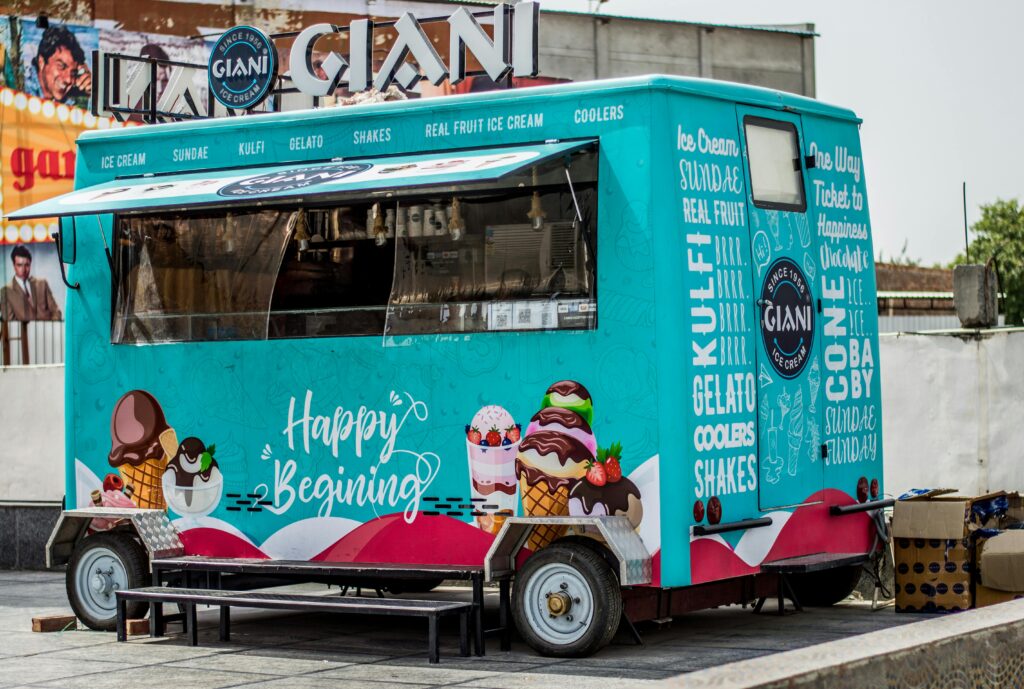 Vibrant ice cream truck parked outdoors offering a variety of sweet treats like gelato and sundaes.