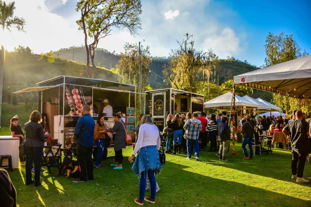 Lively outdoor street food market in Petropolis, Brazil with diverse food carts and a lively crowd.